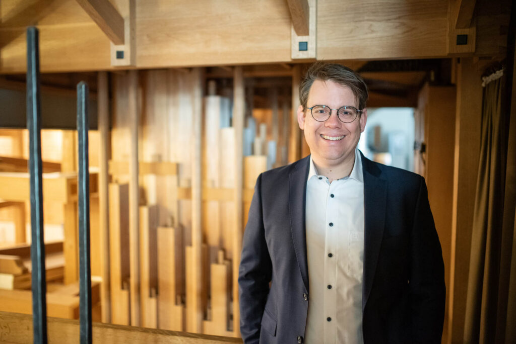 Kai Schöneweiß lächelnd vor den Orgelpfeifen der Stadtkirche St. Marien Celle